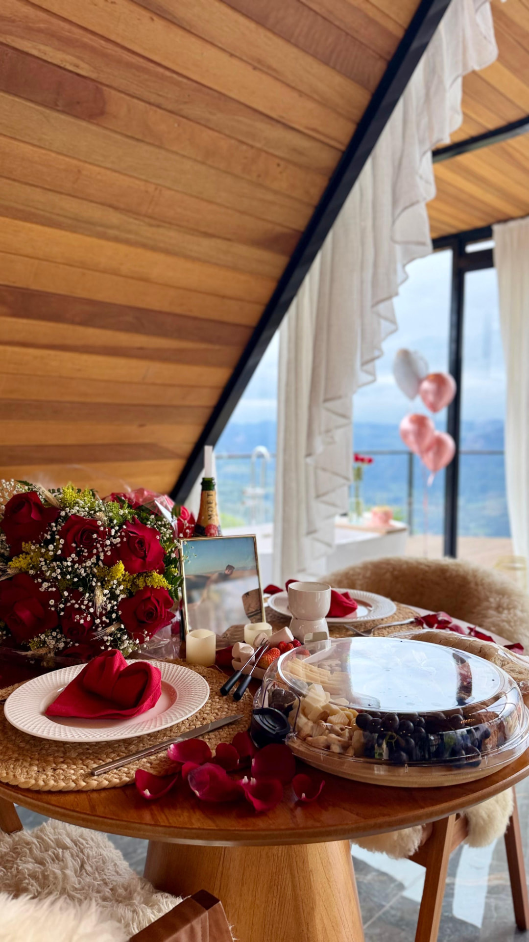 Mesa posta com rosas, tábua de frios e vista para a serra