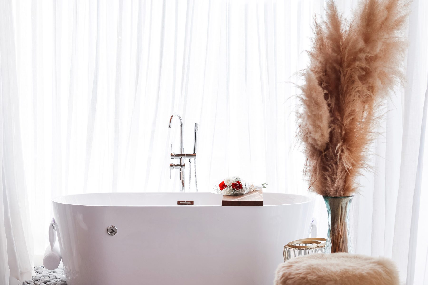 Banheira de imersão com cortinas claras e pampas