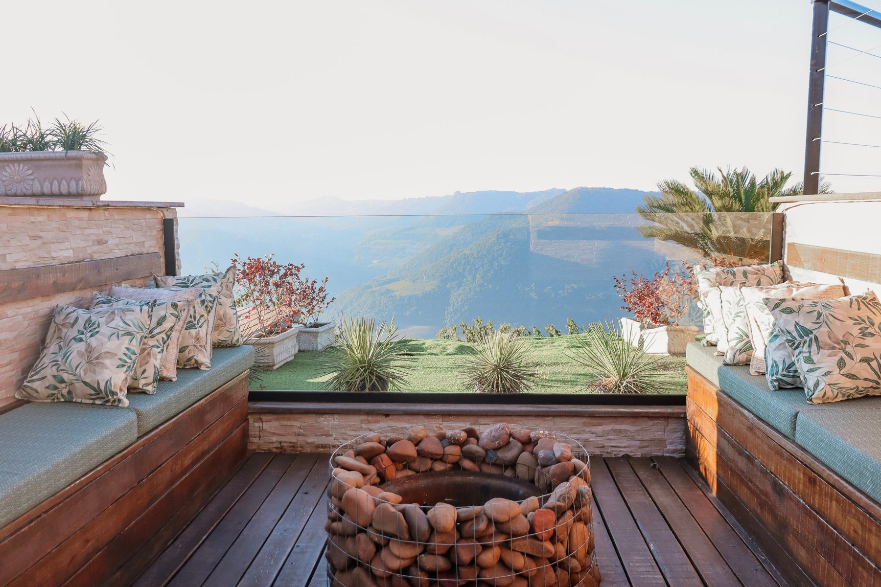 Fire place no deck com almofadas e vista para a serra